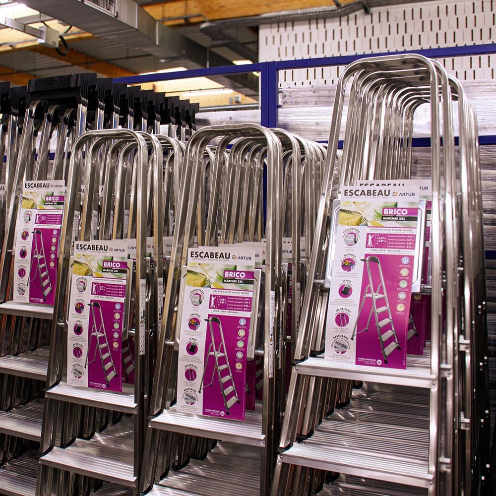 Rows of new silver step ladders displayed in a hardware store aisle with product tags.